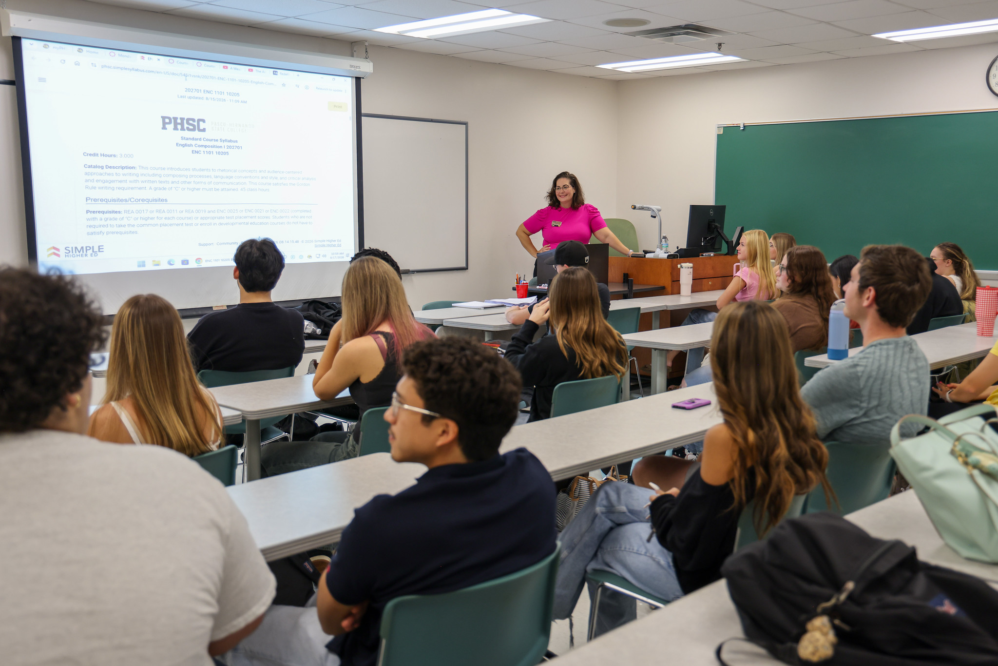 A female PHSC professor standing in front of her classroom while students are sitting.