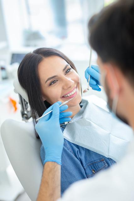 Smiling female patient at dental procedure in dental clinic
