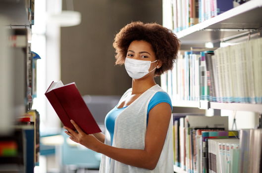 black female wearing face mask holding book