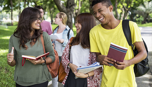 female and male students carrying books while walking and laughing