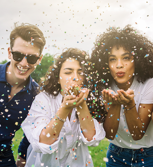 three persons blowing confetti