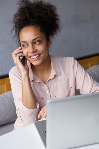 Black female on mobile phone in front of open laptop