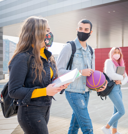 students walking and carrying books, wearing backpacks and face masks