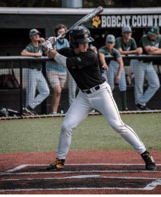 ball player swinging bat at home base