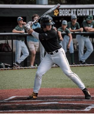 ball player swinging bat at home base