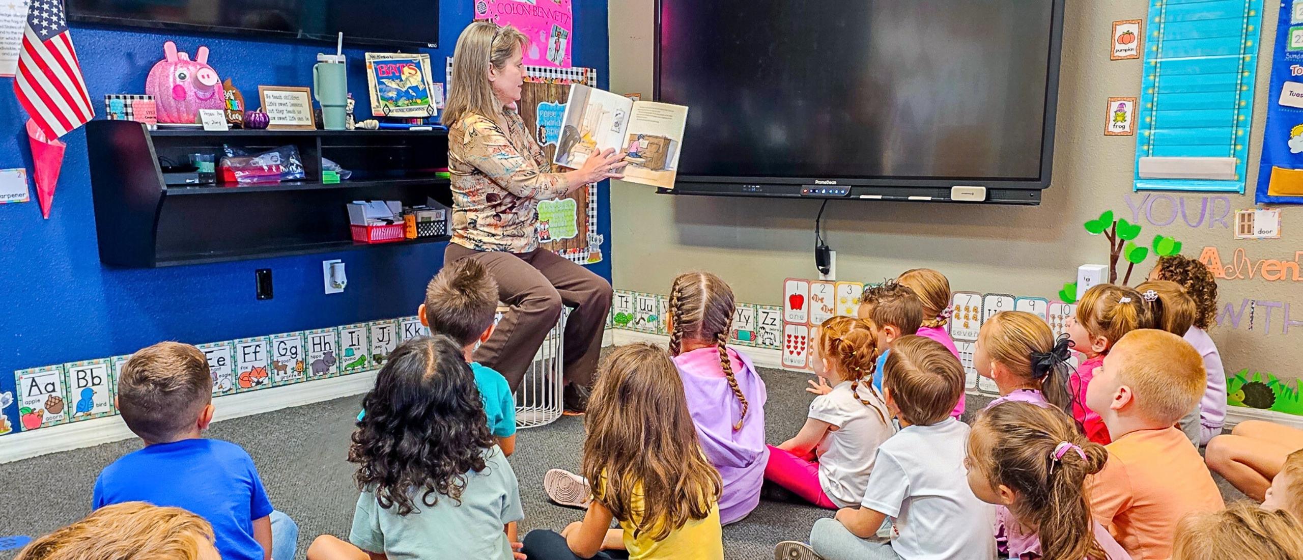 PHSC female staff member reading a book to children.