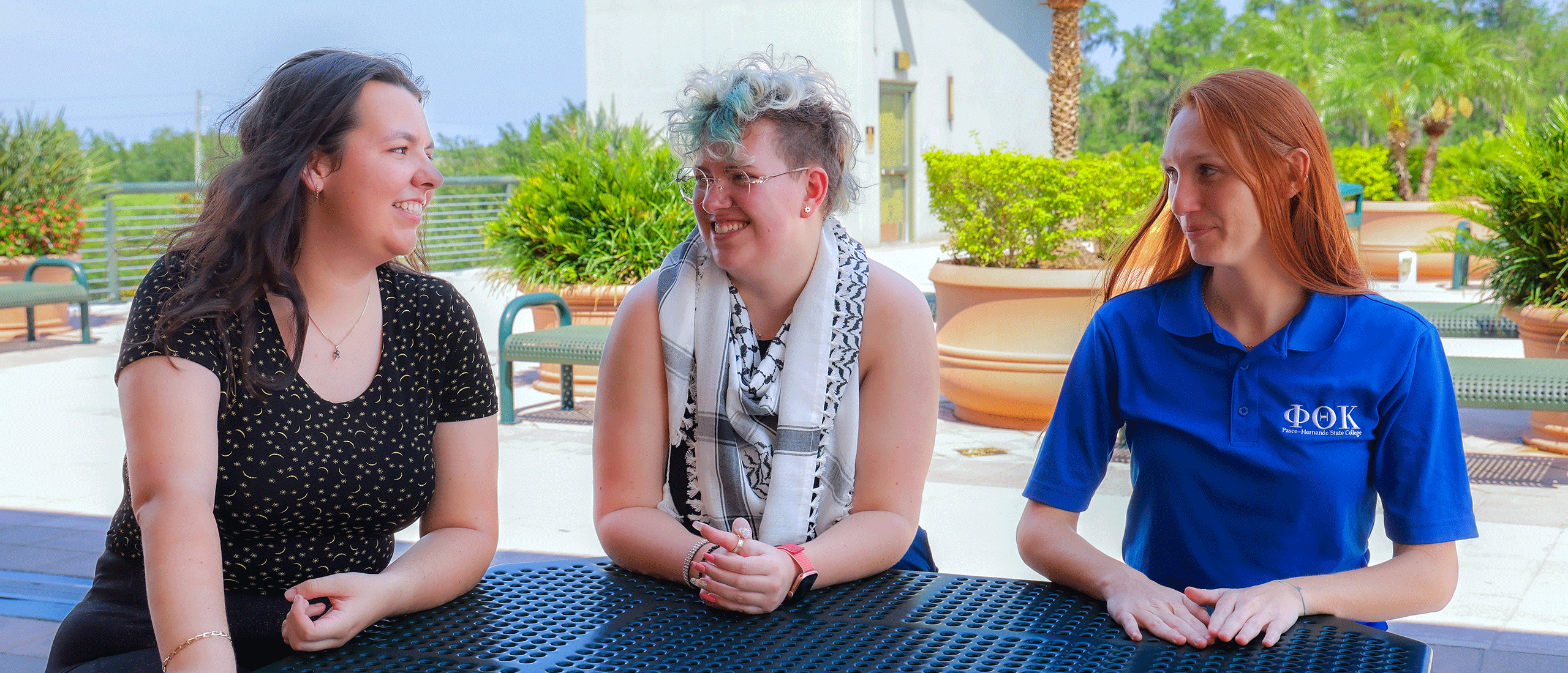 Three PHSC female students sitting outside in a table.