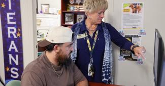 A female PHSC Veterans Advisor helping a male student in front of a computer