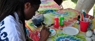 student painting at a table of tie dye colors