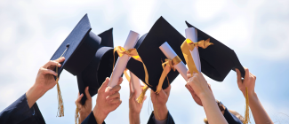 hands holding black mortarboard caps with tasslets and diploma/degrees