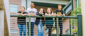 Five diverse students standing next to the balcony.