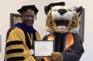 PHSC President Beard poses with PHSC Mascot Boomer holding his diploma