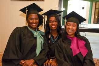 Three African American PHSC female graduates in their caps and gowns
