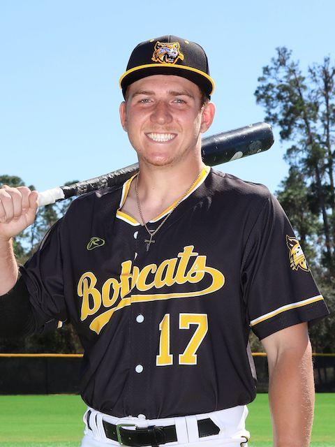 PHSC male baseball outfielder smiling holding a bat on his shoulder