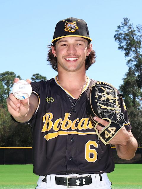 PHSC male baseball player holding a baseball and mitt in his uniform