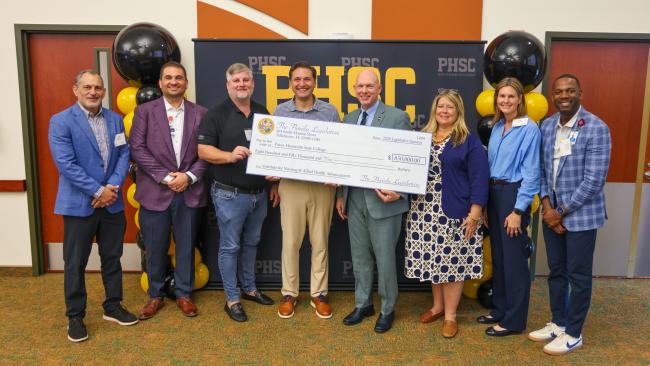 The Institute Executive Committee Meeting Group holding the check at the PHSC Porter Campus at Wiregrass Ranch.
