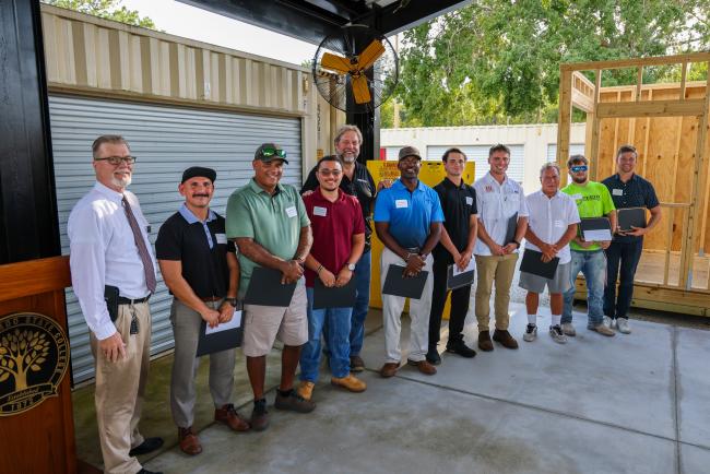 Students and professors standing in a line with their completion certificates.