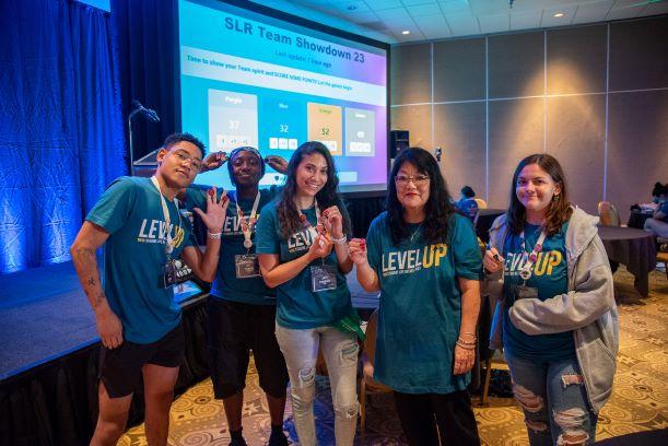 Five diverse students and staff together holding their lanyard charms