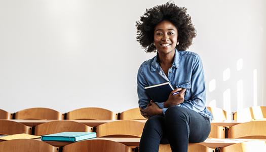 black female holding book and sitting on desk