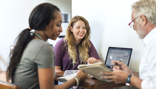 black female and white female meeting with older male reviewing laptop screen